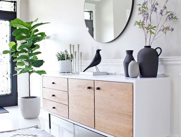 5 minimalistische inneneinrichtung weiße kommode türe aus holz geometrischer teppich skandinavische deko figuren schwarzer vogel vasen weißer topf grüne pflanze runder spiegel