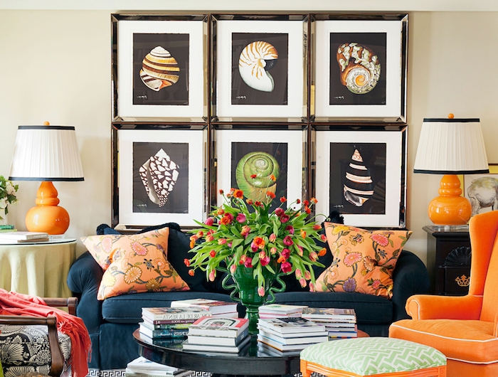 bunte bilder von munscheln vase mit roten tulpen oranger sessel blauer couch orange kissen mit blumenmotiven schwarzer runder tisch wohnzimmer modern einrichten