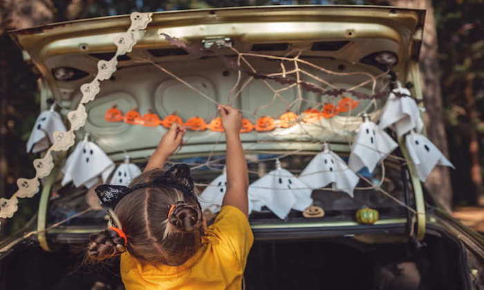 safe distant halloween celebration. kids preparing decoration for party in the trunk of car