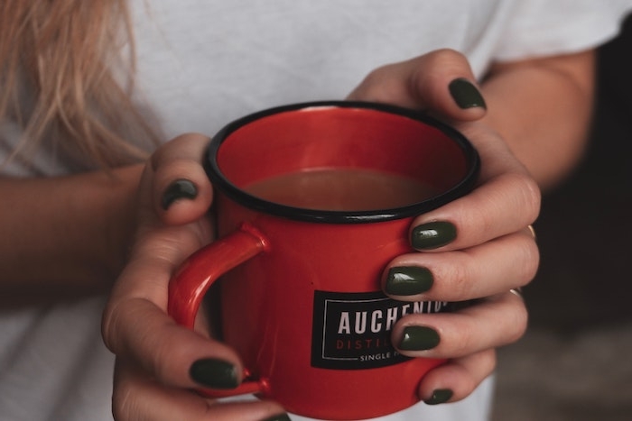 eine große rote tasse mit kaffe eine hand mit einem dunklen nagellack und mit einem weißen t shirt