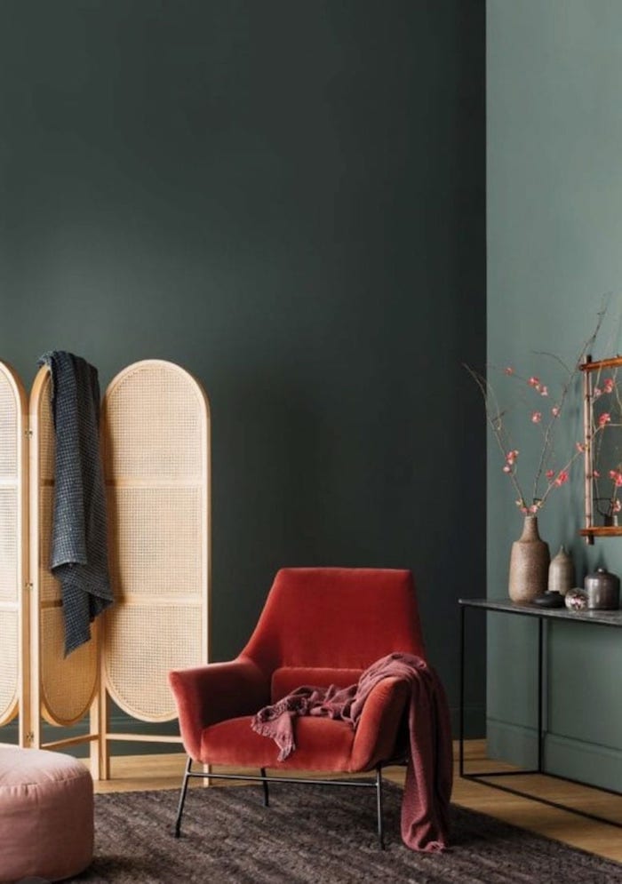 eleganter roter sessel wandfarbe grün skandinavische deko wohnzimmer spanische wand holz dunkler teppich pinker ottoman