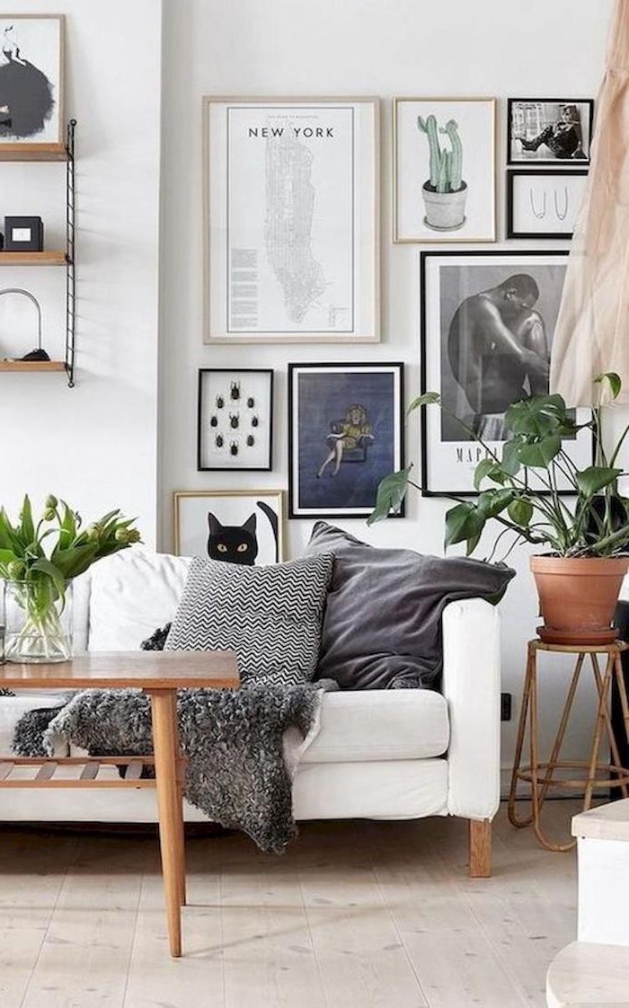 gemütliches elegantes skandinavisches wohnzimmer ideen bilderwand inspiration weißer couch mit holzbeinen deko nordisch grüne pflanze scharze