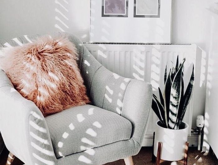 gemütliches zimmer einrichten wanddekoration wohnzimmer graues sofa flauschiger pinker kissen weiße vase grüne pflanze schwarz violett quadrate abstraktes gemälde
