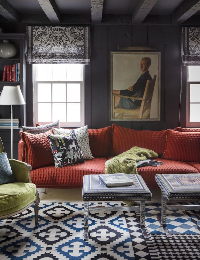 großes couch rot weiß blau schwarzer teppich wohzimmer ideen modern bunte kissen großes gremälde von einem mann schwarze jalousien
