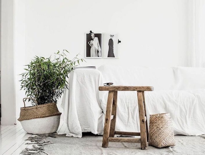 interior design scandi style wohnzimmer korb topf dekoratiover kleiner baum hocker skandinavisch aus holz großer couch bedeckt mit weißer decke schwarz weiße bild an die wand