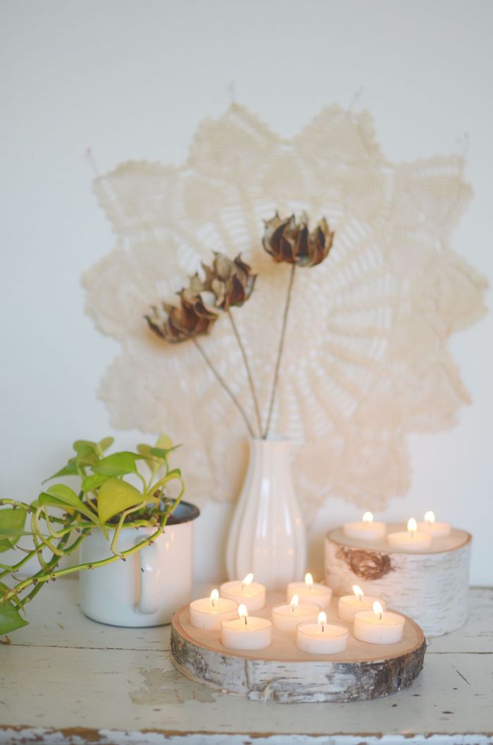 makramee wanddeko blumenmuster weiße vase blumen holzstamm deko holzscheiben kerzenhalter teelichter dekoration wohnzimmer inspo