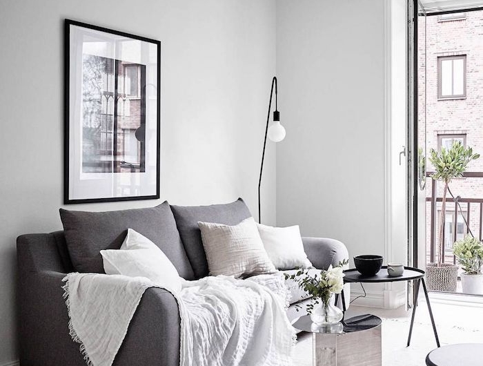 minimalistische inneneinrichtung interior design inspo wohnzimmer ideen modern großes schwarz weißes bild an die wand grauer couch weiße kissen und decke kaffeetisch schwarz