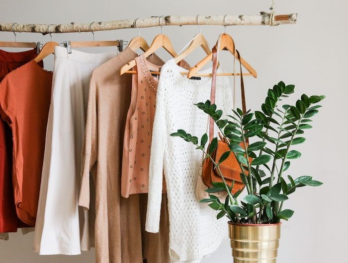 minimalistischer kleiderständer goldene vase grüne pflanze garderobe birkenstamm deko weiße sneaker aufgehängte klamotten wandfarbe weiß