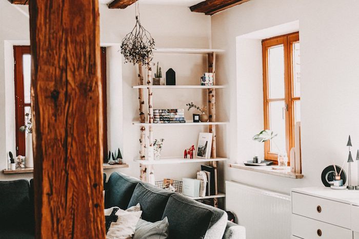 moderne inneneinrichtung birkenstamm deko wohnzimmer regale aus birkenäste großer schwarzer sofa decke mit holzbalken wandfarbe weiß