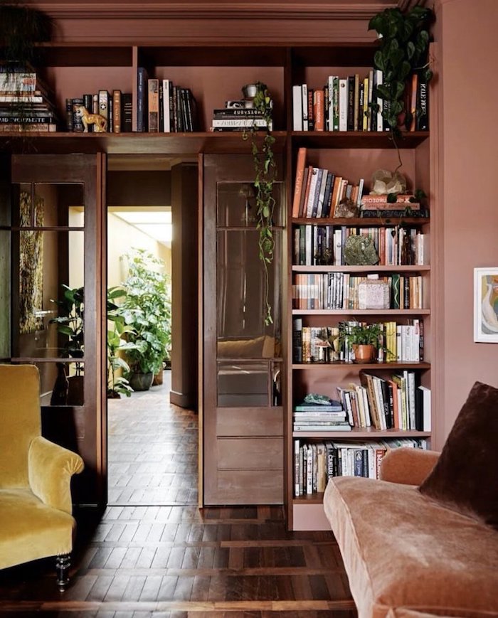 regal mit büchern wandfarbe altrosa gelber sessel vintage wohnung warme farben wohnzimmer ideen modern einrichten grüne pflanze interior design trends 2020 inspo