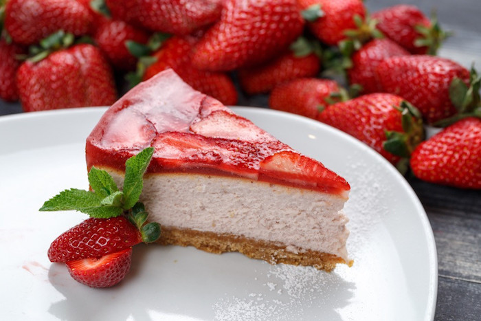 rezept für kuchen mit quark weißer teller mit einem stück kuchen mit roten erdbeeren und frischer pfefferminze viele kleine frische erdeeren