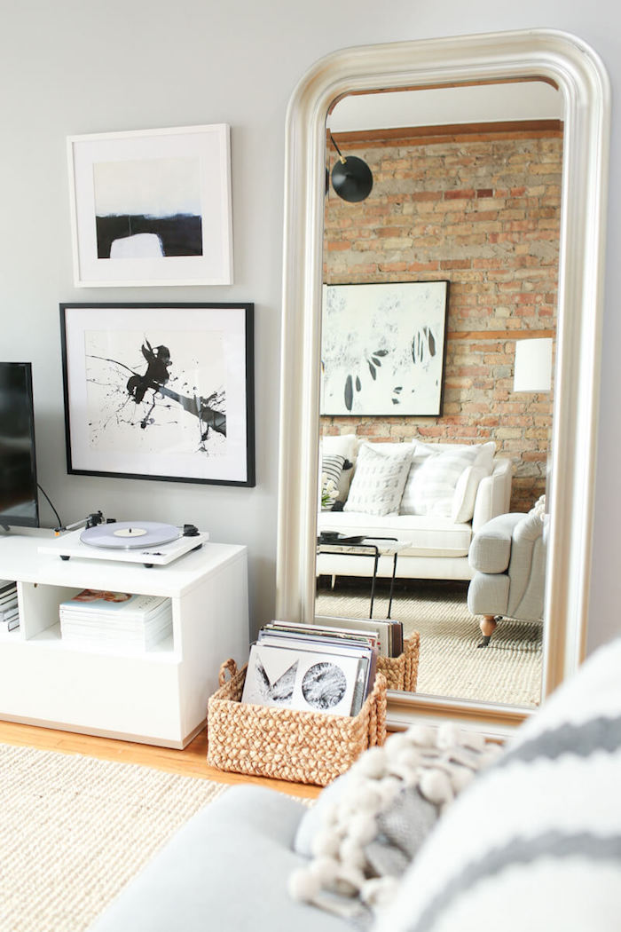 rote ziegelsteinmauer kleinen wohnraum einrichten deko wohnzimmer modern schwarz weiße bildeer an die wand kleiner kasten mit schallplatten weißer couch deko kissen