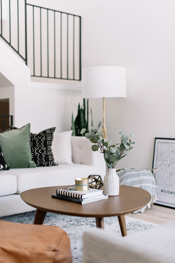 scandi style innenausstatting runder kaffeetisch wohnzimmer einrichten modern weiße vase grüne pflanzen cremefarbener couch schwarze grüne deko kissen skandinavische einrichtung interior design 2020