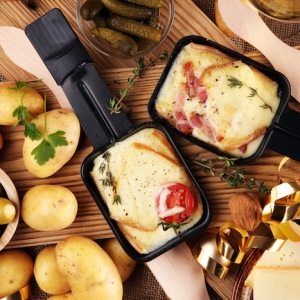 schinkeln grüne oliven kartoffeln und gewürze tomaten und geschmolzener käse im pfännchen für raclette
