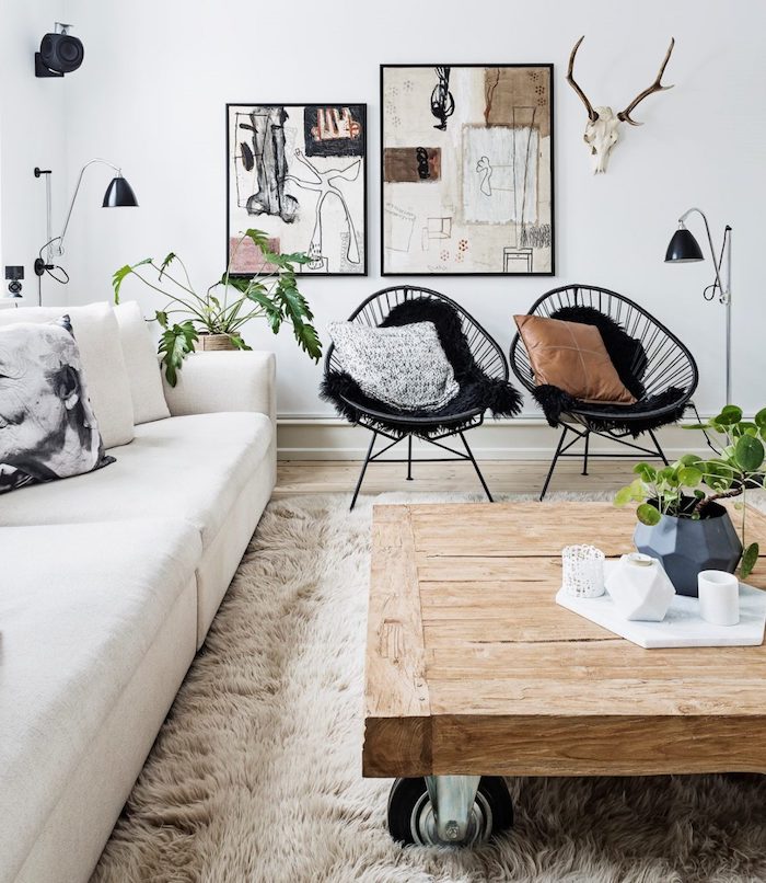 skandinavischer design inneneinrichtung inspiration holztisch mit rädern schwarze stühle weißer couch abstrakte gemälde wanddeko deko wohnzimmer modern interior design minimalistisch