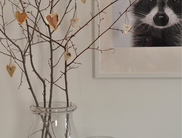 valentinstag dekoration schwarz weißes foto von einem waschbär kleine vase mit weißer kerze birken deko herzen aus birkenstamm aufgehängt auf dünne zweige
