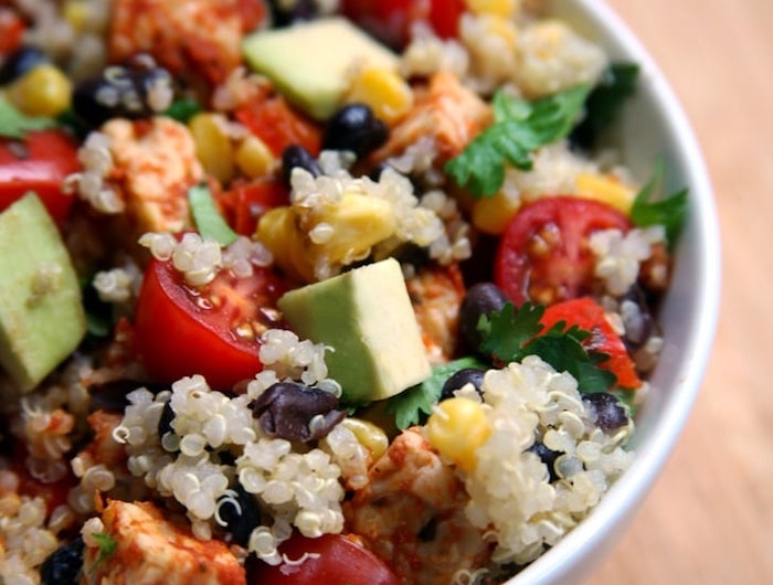 veganer buddah bowl schnelles abendessen salat mit quinoa tomaten avocado petersilie mais schwarze bohnen weiße schüssel gesunde rezepte
