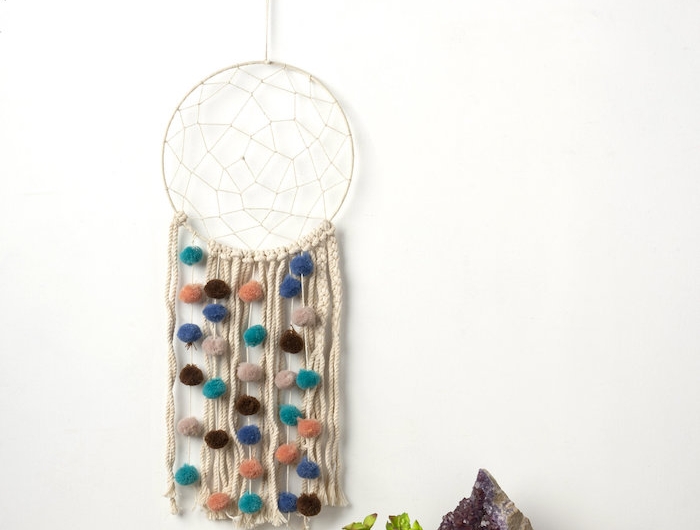 wandhänger makramee wanddeko diy aus baumwolle dekorative bunte bällchen vase mit kleiner grüner kaktee quartz stein lila minimalistische einrichtung