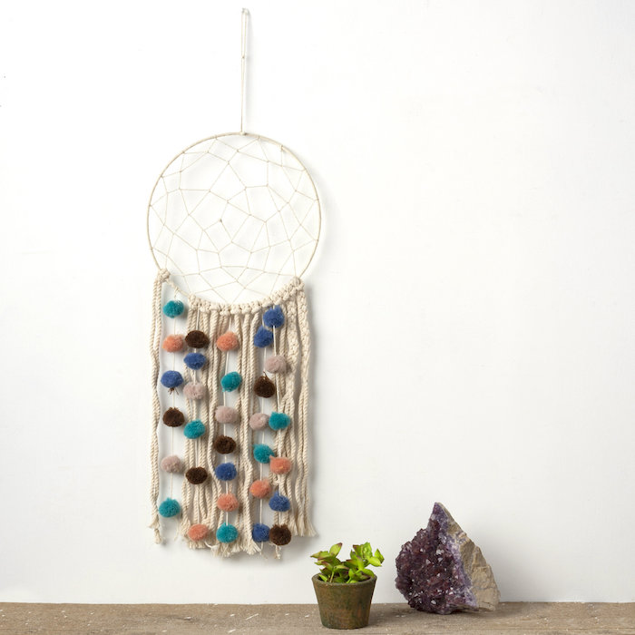 wandhänger makramee wanddeko diy aus baumwolle dekorative bunte bällchen vase mit kleiner grüner kaktee quartz stein lila minimalistische einrichtung