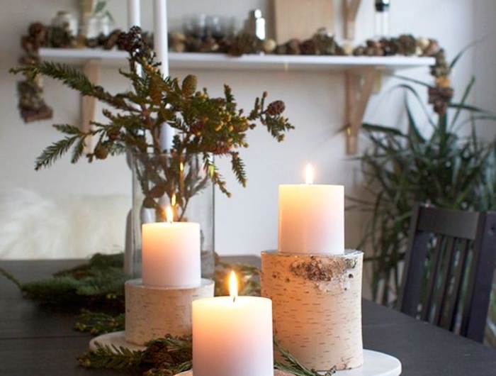 weihnachten dekoration inspiration holzstamm deko kerzenhalter aus birkenholz große weiße kerzen grüne tannenzweige wohnzimmer deko festlich großer esstisch offene regale