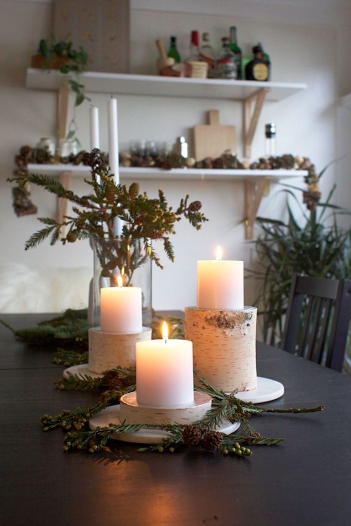 weihnachten dekoration inspiration holzstamm deko kerzenhalter aus birkenholz große weiße kerzen grüne tannenzweige wohnzimmer deko festlich großer esstisch offene regale