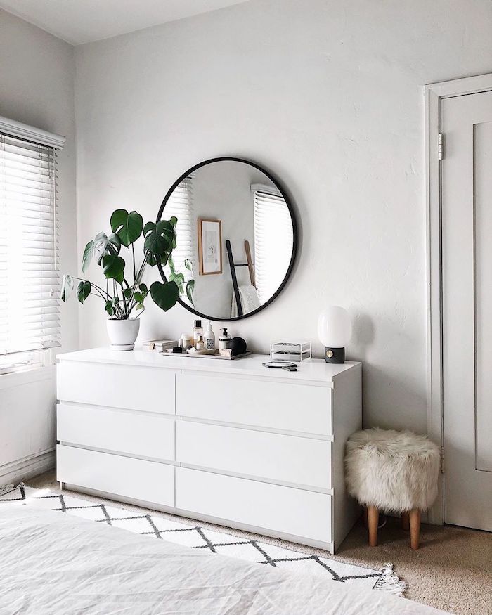 weiße kommode skandinavische einrichtung schlafzimmer runder spiegel mit schwarzem rahmen deko grüne pflanze hocker skandinavisch flauschige polsterung zimmer weiße ästhetik