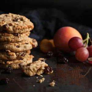 homemade organic oatmeal cookies with raisins and apricots on dark wooden background with apricot and grapes.