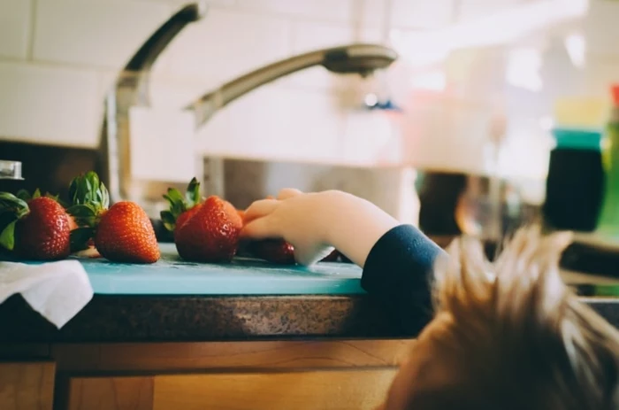 lerntower information montessori kind streckt sich um erdbeere zu holen