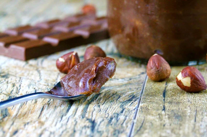 löffel aus metall und mit einer veganen nutella alternative ein glas mit nutella