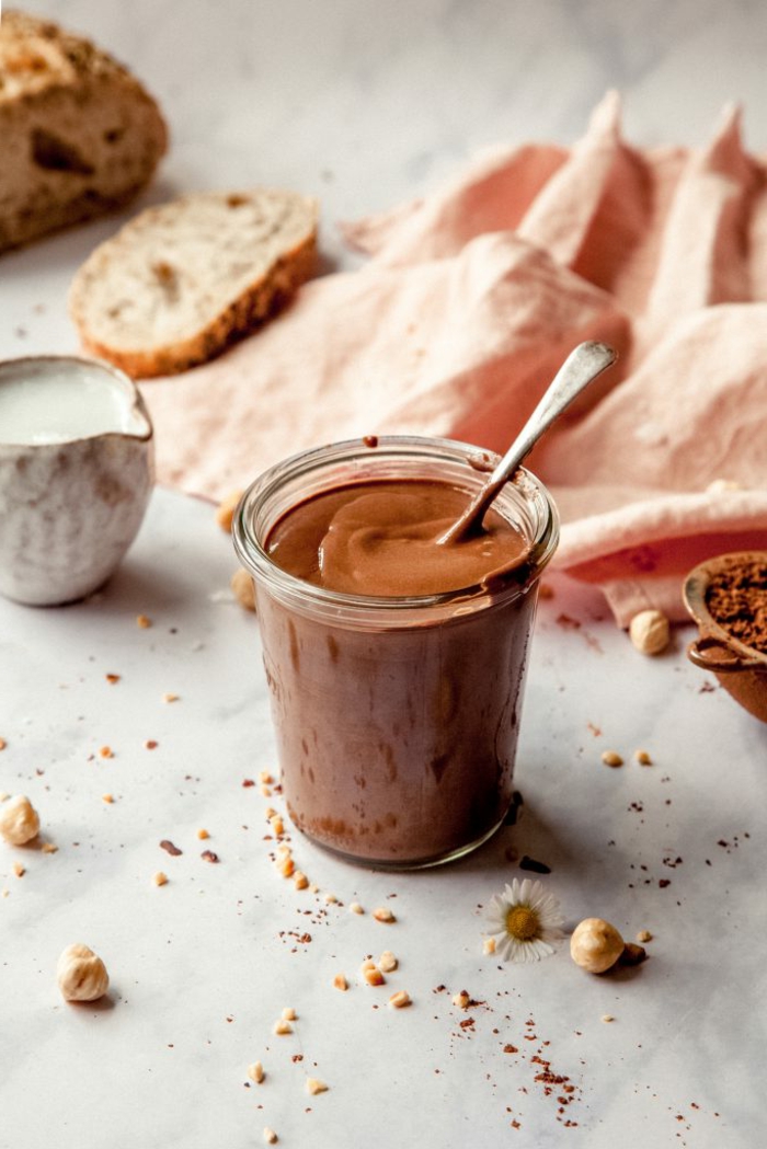 nutella selber machen mit milch und honig und haselnüssen ein glas mit schockocreme und haselnüssen