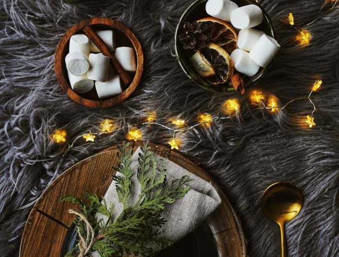 weihnachtstisch kreativ dekorieren teller aus holz servietten falten modern tannenzweig deko kleine lichterketten marschmallows flauschige graue decke