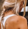 blonde frau lange haare im zopf weißes top originelle tattoo ideen minimalistisch kleines schwarzes herz tätowierung
