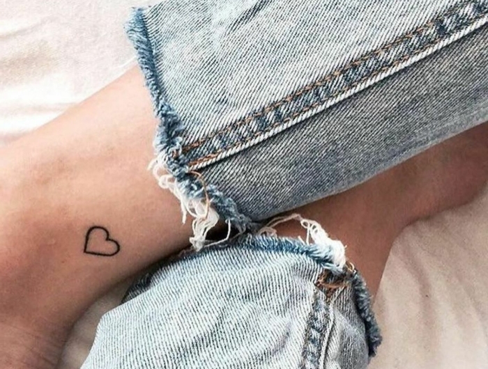 frau in jeans bedeutung tattoo motive klein schwarzes herz fußgelenk minimalistisches design