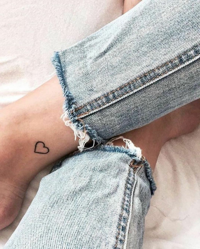 frau in jeans bedeutung tattoo motive klein schwarzes herz fußgelenk minimalistisches design 