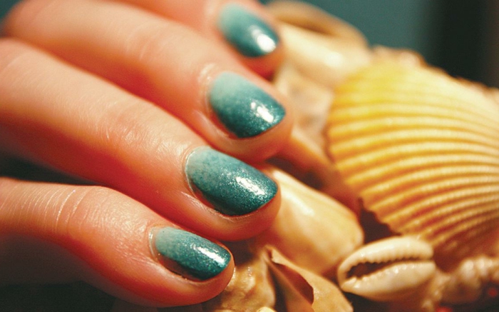 große muschel ombre nails in verschiedene blautöne dame mit moderner maniküre kurze fingernägel runde nagelform
