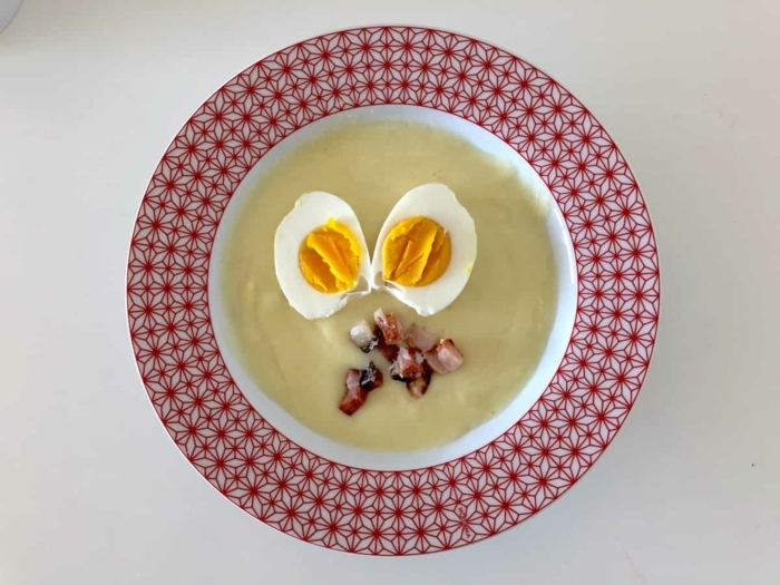 speck und zwei gekochte eier ein roter teller mit suppe mit meerrettich