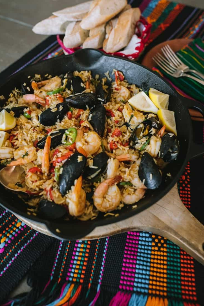bunte tischdecke paella mit meeresfrüchten garnellen und miesmuscheln reisgerichte spanisch ideen abendessen kochen teller mit brot