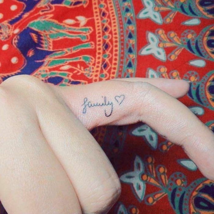 buntes tuch hand mit tätowiertem ringfinger wort family mit einem kleinen herz tattoo ideen familie inspiration