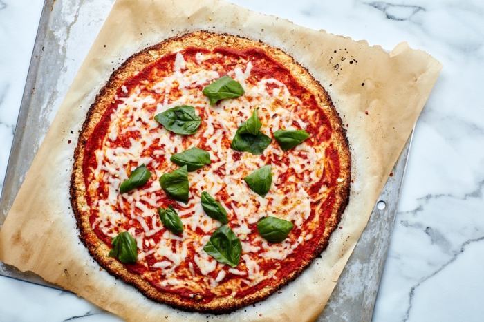 ein brett aus holz eine blumenkohl pizza mit basilikum und tomaten soße