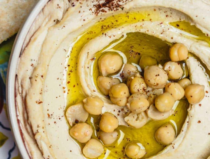 eine schüssel mit einem beigen hummus mit olivenöl und kichererbsen