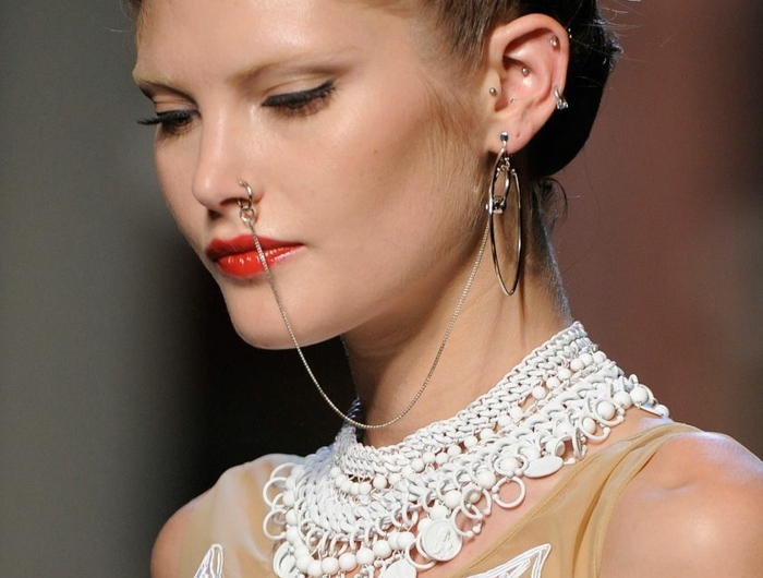 fashion week show elegantes kleid mit spitze model mit braunen haaren roter lippenstift nasenring gold mit kette viele ohrringe