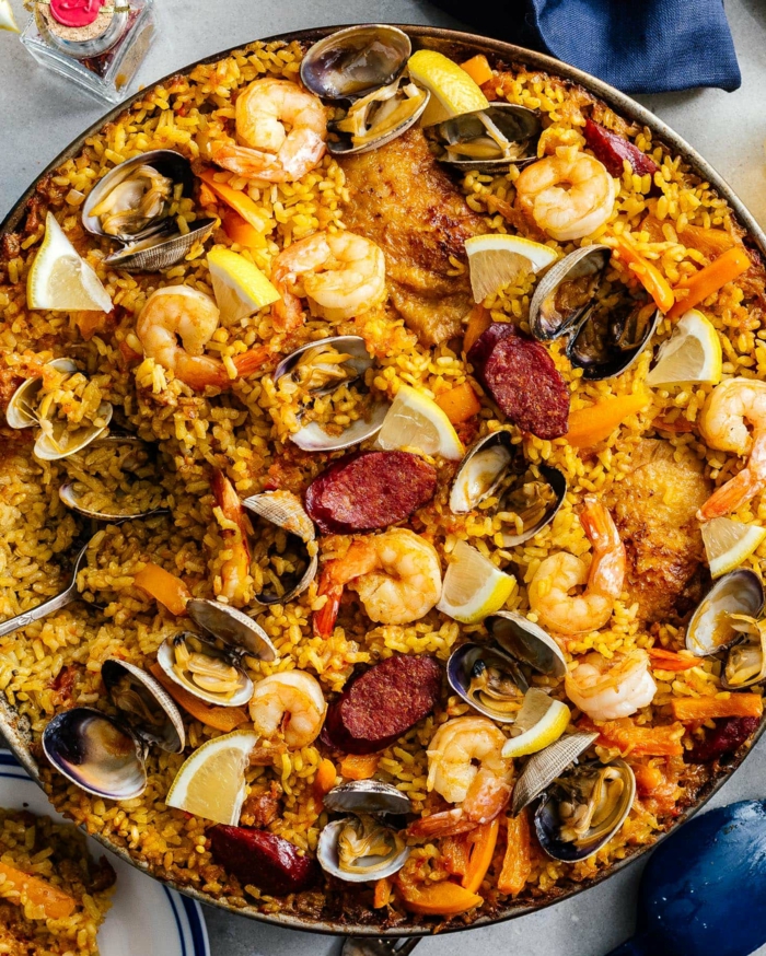 große schale spanische reisespeise leckere paella rezepte inspiration reis mit meeresfrüchten und fleisch zitronen