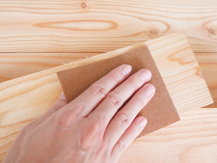 hand sanding wooden pallet with sandpaper