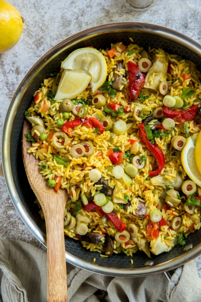 leckere rezepte abendessen ideen paella reis mit gemüse und oliven großer löffel aus holz klassische speisen spanien