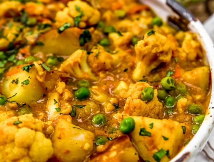tisch aus holz ein teller mit einem blumenkohl curry mit petersilie und kurkuma