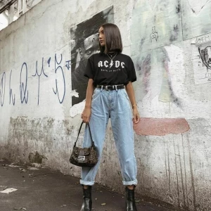 ac dc t shirt schwarz klassisches outfit street style hellblaue jeans damen slouchy style schwarze boots und tasche dame mit kurzen haaren