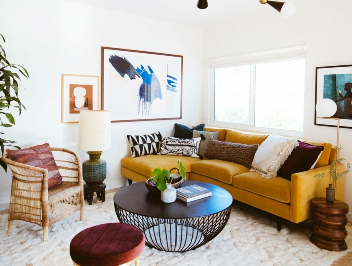 eleganter gelber sofa deko kissen schwarzer kaffee tisch weißer flauschiger teppich gemälde an die wand wohnzimmer skandinavischer stil