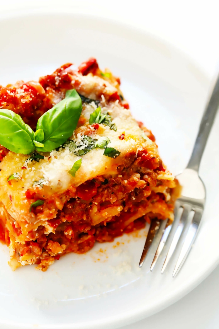 gabel und lasagne mit tomaten soße faschiertes und käse ein weßer teller