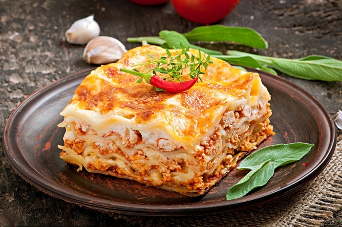 knoblauchzehen und zwiebeln ein teller mit lasagne mit frischen tomaten und parmesan