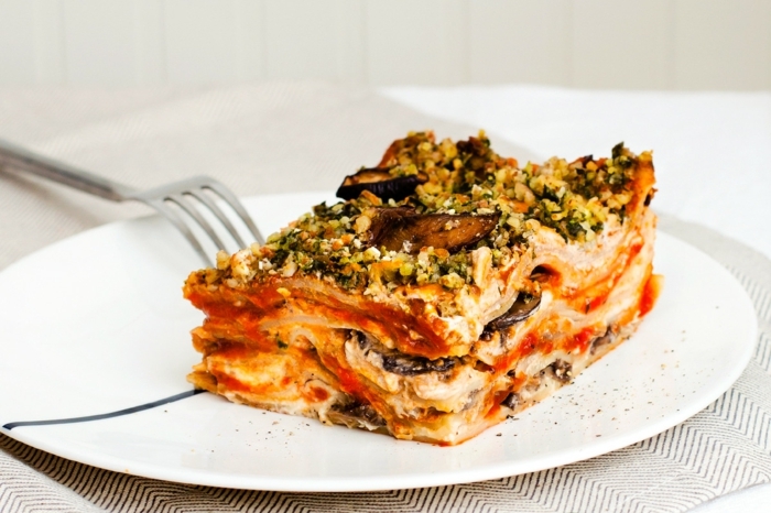 lasagne mit spinat und aubergine ein weißer teller eine gabel